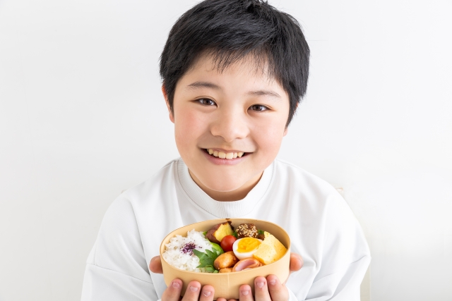 お弁当を持って笑顔の少年