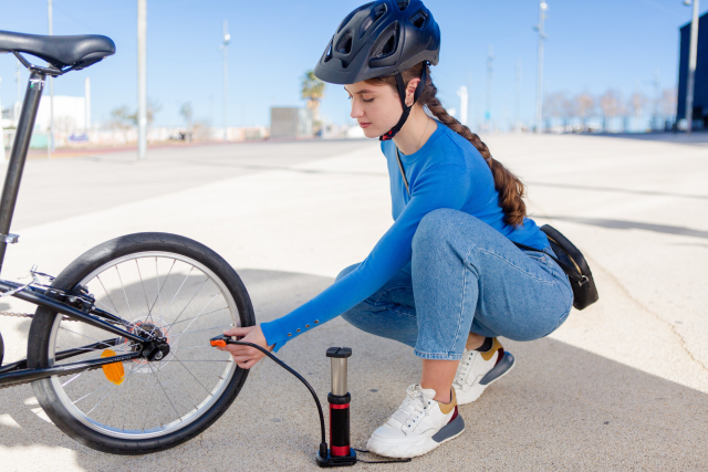 自転車のタイヤに空気を入れる女性