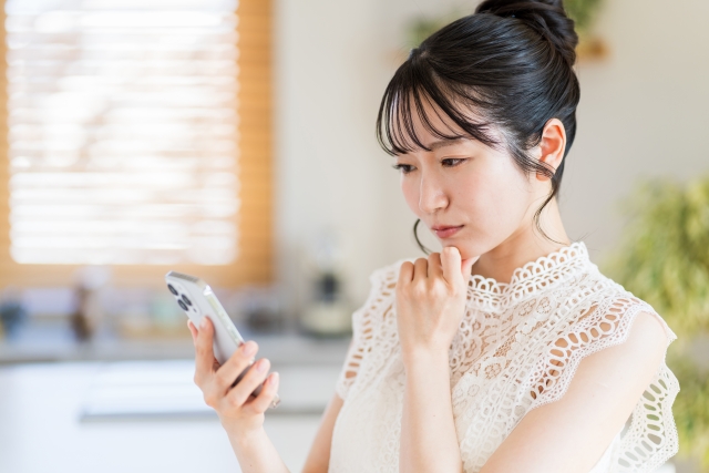 スマホを見ながら不安そうな女性