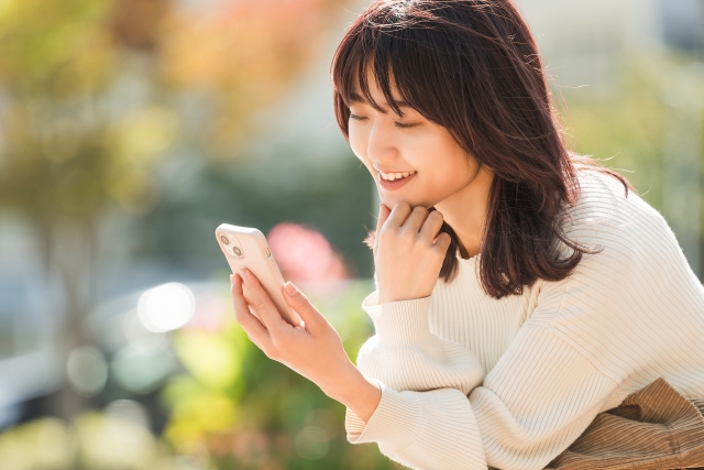 笑顔でスマホを見る女性