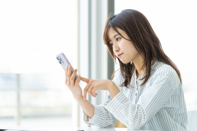 スマホを見ながら悩む女性